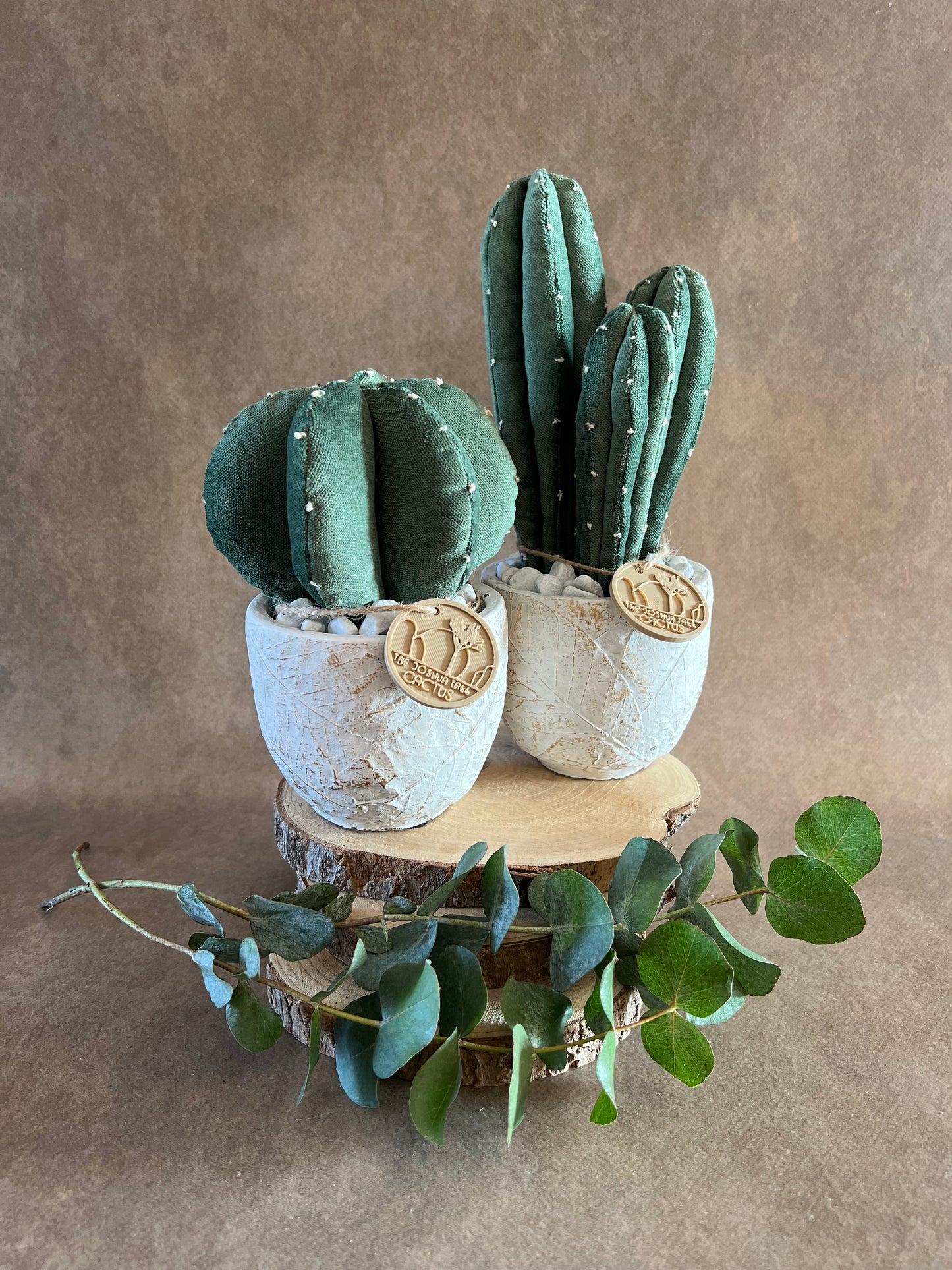 Coppia di composizioni ricamate in vellutino verde, vaso in cemento con motivi a foglia, h circa 19 e 27 cm